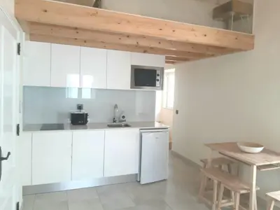 a kitchen with white cabinets and a wooden table at Casa aOrta Studios in Faro