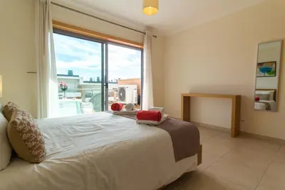 a bedroom with a bed and a large window at Albufeira Stylish Townhouse in Albufeira