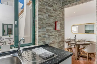 a kitchen with a sink and a dining table at Casa dos Sonhos Albufeira in Albufeira
