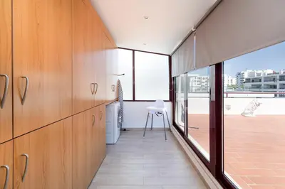 a kitchen with wooden cabinets and a large window at Centralgarve - Beachfront with Pool Penthouse in Quarteira