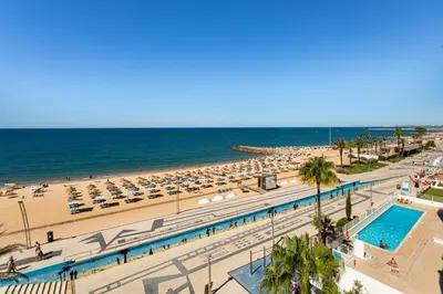 a view of a beach with umbrellas and the ocean at Centralgarve - Beachfront with Pool Penthouse in Quarteira