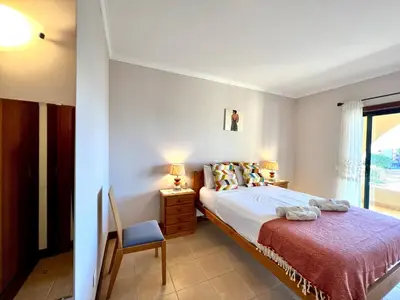 a bedroom with a bed and a chair and a window at Albufeira Salgados Beach 3 by Homing in Albufeira