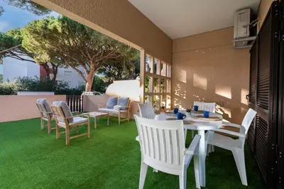 a patio with a white table and chairs on grass at ALEGRIA 29 - T2 piso terreo com AC e piscina by My Algarve Rentals in Quarteira