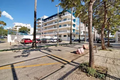 a street with cars parked in front of a building at Lovely one bedroom apartment in Quarteira