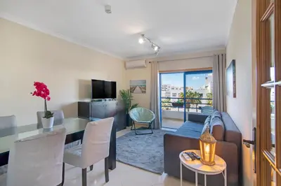 a living room with a couch and a table with chairs at Lovely one bedroom apartment in Quarteira