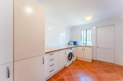 a kitchen with white cabinets and a washer and dryer at Villa Breena - Quinta do Mar in Almancil