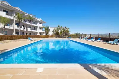 a swimming pool with lounge chairs and a building at Apartamento T1 - Em zona tranquila in Olhos de Água