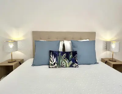 a bedroom with a bed with blue pillows and two lamps at Sun II - City center by HD PROPERTIES in Vilamoura