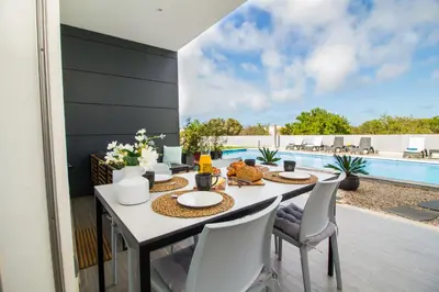 a dining room with a table and chairs and a pool at By the sea, Algarve in Galé