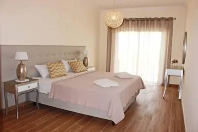a white bedroom with a large bed and a window at Apartment Amelo in Albufeira