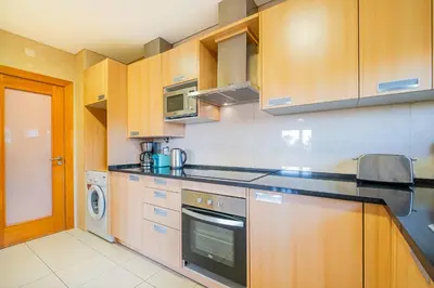 a kitchen with wooden cabinets and a washer and dryer at Apartment Oura - Views of sea, Albufeira bay & Old Town in Albufeira