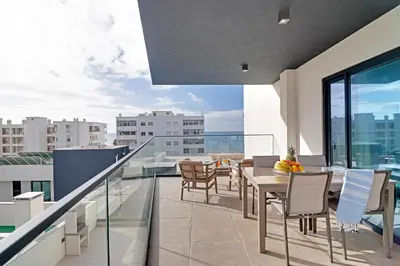 a balcony with a table and chairs on a building at Sky Beach Apartment in Quarteira