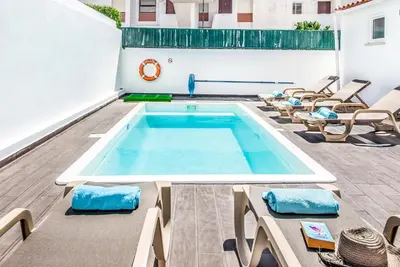 a swimming pool in a building with chairs around it at Villa Mitto in Albufeira