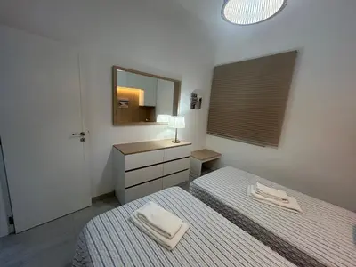 a white bedroom with two beds and a mirror at Casa Garcia in Quarteira