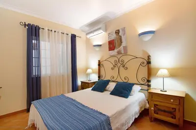 a bedroom with a white bed and wooden cabinets at Villa Guisado in Albufeira
