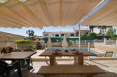a patio with tables and umbrellas and a pool at Villa Guisado in Albufeira