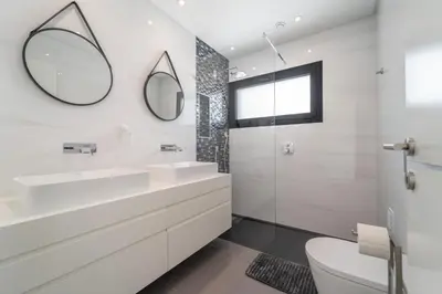 a white bathroom with two sinks and a mirror at Villa das Amendoeiras by HelloVacations in Albufeira
