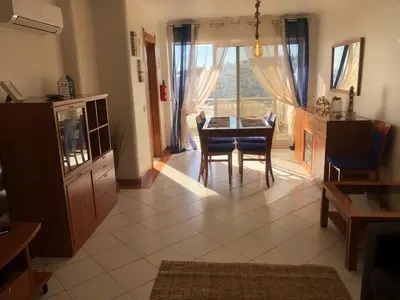 a living room with a television and a dining room at Beachfront 2 bedroom apartment in Albufeira