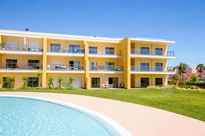 a large yellow building with a swimming pool in front of it at Marina Jardim - Great complex for families in Albufeira