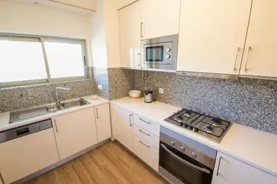 a kitchen with white cabinets and a stove top oven at Marina Jardim - Great complex for families in Albufeira