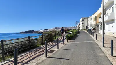a sidewalk next to a beach with buildings and the ocean at Albufeira, Modern Sea View Home 33 in Albufeira