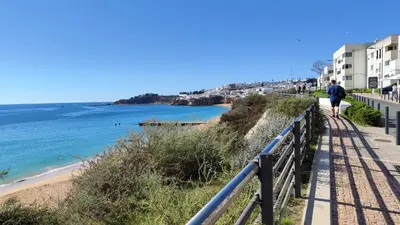 a man walking down a path next to a beach at Albufeira, Modern Sea View Home 33 in Albufeira