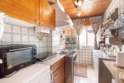 a kitchen with wooden cabinets and a microwave at T3 Duplex Albufeira in Olhos de Água