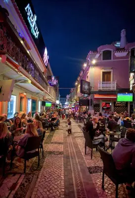 a crowd of people sitting in chairs on a street at night at Holiday Albufeira in Albufeira