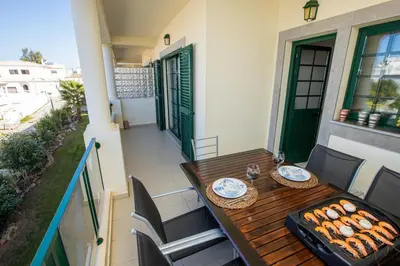 a wooden table on a balcony with a grill at Holiday Albufeira in Albufeira