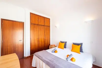 a bedroom with a bed with orange and blue pillows at Villa Bermudas by Algarve Vacation in Albufeira