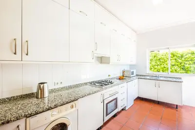 a kitchen with white cabinets and a red tile floor at Villa Bermudas by Algarve Vacation in Albufeira