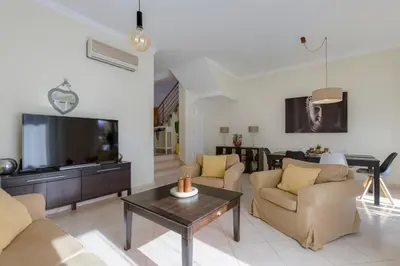 a living room with a couch and a tv and a table at BALAIA RESIDENCE - Fantástica moradia para 6 com piscina e BBQ in Olhos de Água