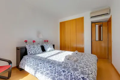 a bedroom with a bed with a blue and white bedspread at BALAIA RESIDENCE - Fantástica moradia para 6 com piscina e BBQ in Olhos de Água