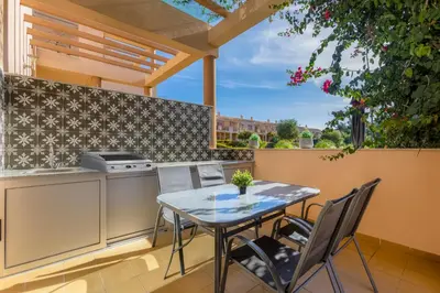 a patio with a table and chairs and a kitchen at BALAIA RESIDENCE - Fantástica moradia para 6 com piscina e BBQ in Olhos de Água