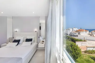 a bedroom with a white bed and a large window at Coração do Mar by OCvillas in Albufeira