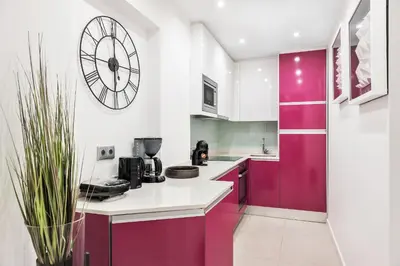 a kitchen with purple cabinets and a clock on the wall at Coração do Mar by OCvillas in Albufeira