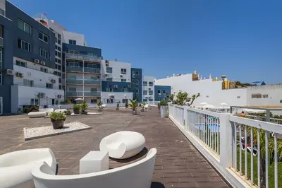 a balcony with white chairs and tables and buildings at Coração do Mar by OCvillas in Albufeira