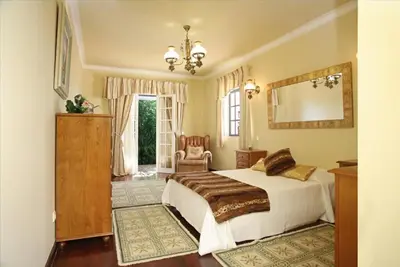 a bedroom with a bed and a mirror and a chair at Villa Juniper fenced pool spacious house in Albufeira