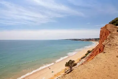 a beach with people walking on it next to the ocean at Apartamento Kaya by Sunnyway in Albufeira