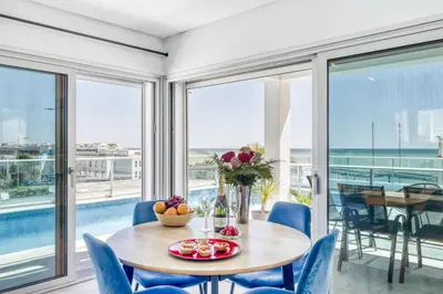 a dining room with a table and chairs and windows at Ocean Chic by the Beach in Albufeira