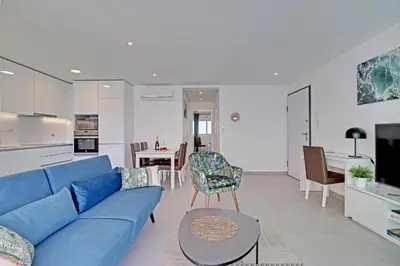 a living room with a blue couch and a kitchen at Ocean Chic by the Beach in Albufeira