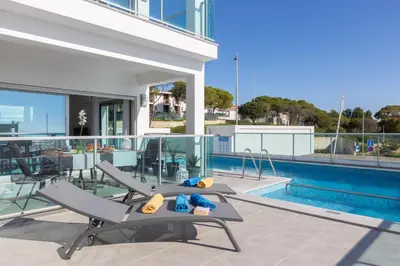 a swimming pool with two lounge chairs next to a house at Ocean Chic by the Beach in Albufeira