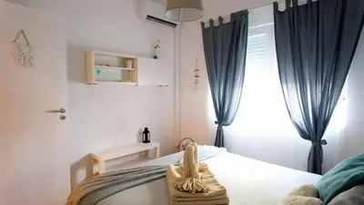 a bedroom with a bed with blue curtains and a window at BENAMAR HOUSE in Quarteira