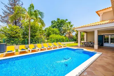 a swimming pool with chairs and a house at Villa Hawaii by Algarve Vacation in Albufeira