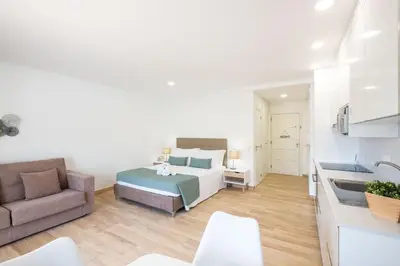 a bedroom with a bed and a couch and a kitchen at Studio Pimenta - Short walk to the beach in Albufeira