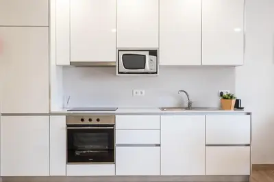 a white kitchen with a microwave and a sink at Studio Pimenta - Short walk to the beach in Albufeira
