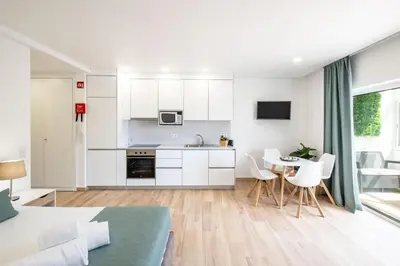 a kitchen and living room with white cabinets and a table at Studio Pimenta - Short walk to the beach in Albufeira
