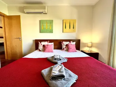 a bedroom with a red bed with towels on it at Albufeira Modern 3 With Pool by Homing in Albufeira
