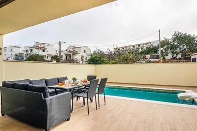 a dining room with a table and chairs next to a swimming pool at BeGuest Albufeira Luxus Villa in Albufeira
