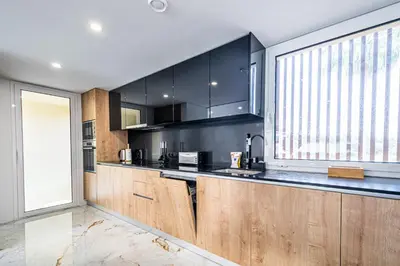 a kitchen with wooden cabinets and a large window at BeGuest Albufeira Luxus Villa in Albufeira